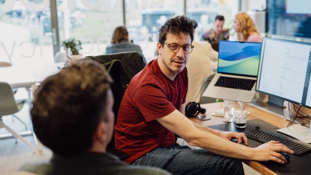 Foto van Aron van der Valk in gesprek met een collega in het kantoor van Two fifty